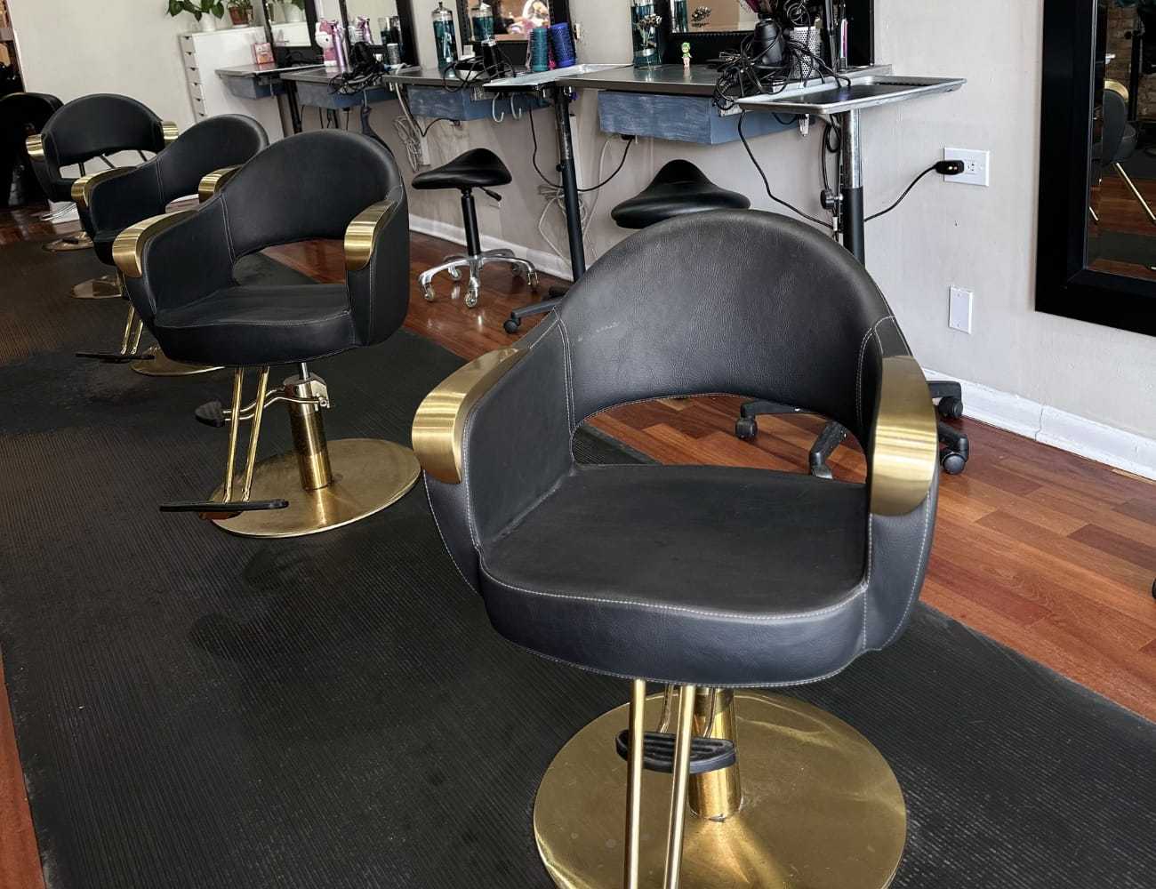 Black salon chairs at a stylish hair salon, featuring modern equipment and hardwood flooring.