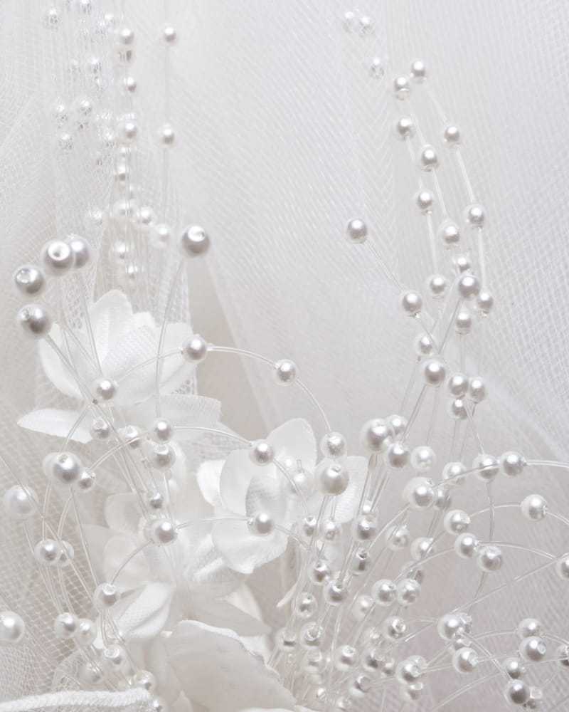 Delicate white fabric with floral and pearl embellishments.