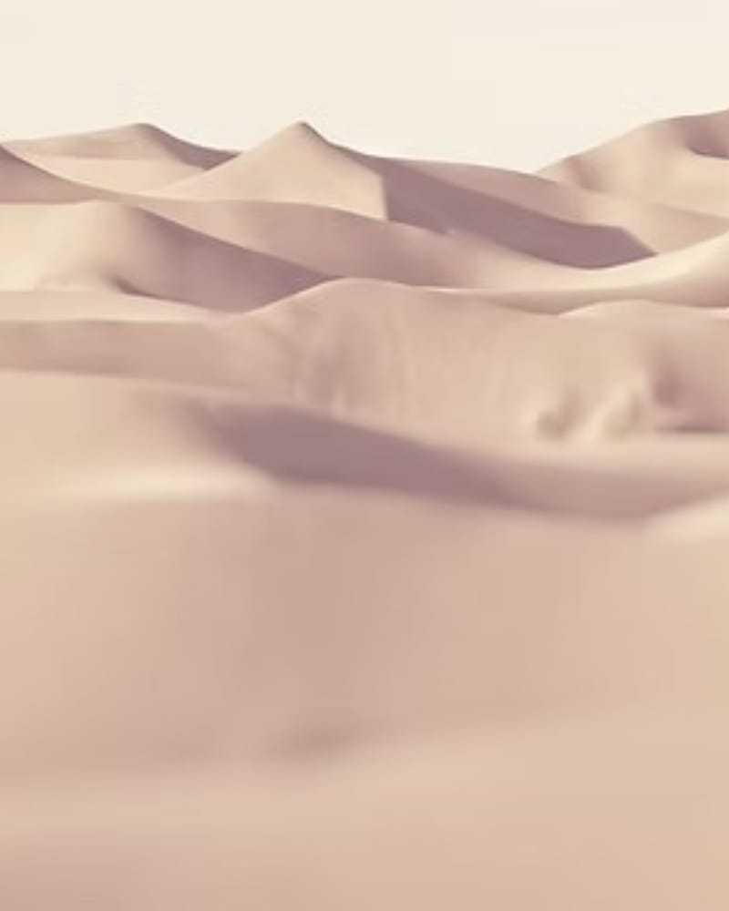 Smooth, abstract sand dunes under soft lighting, creating a serene and minimalist landscape.
