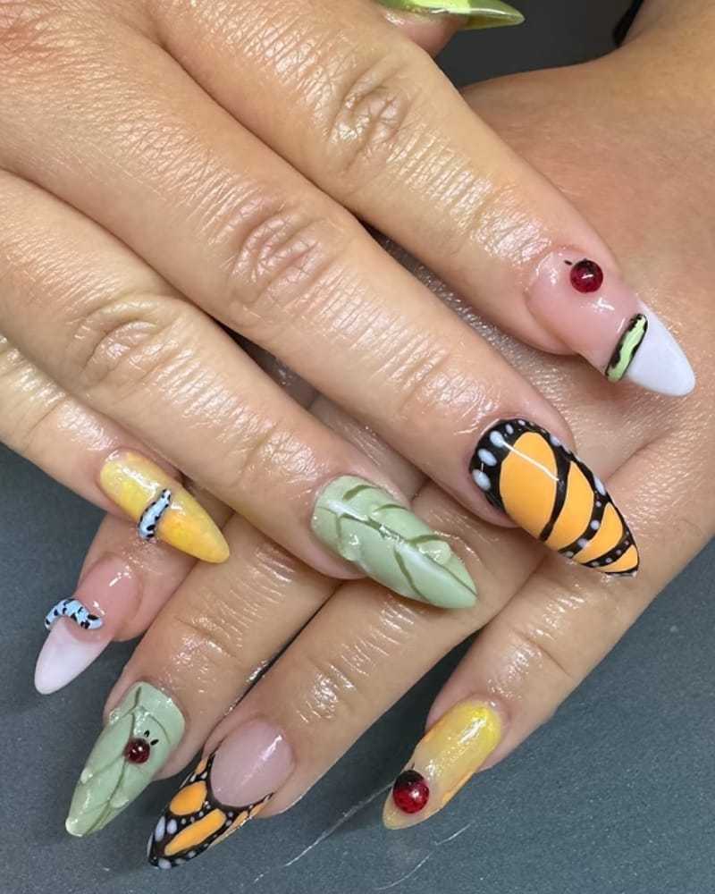 Butterfly-themed nail art with bright colors and 3D elements on hands.
