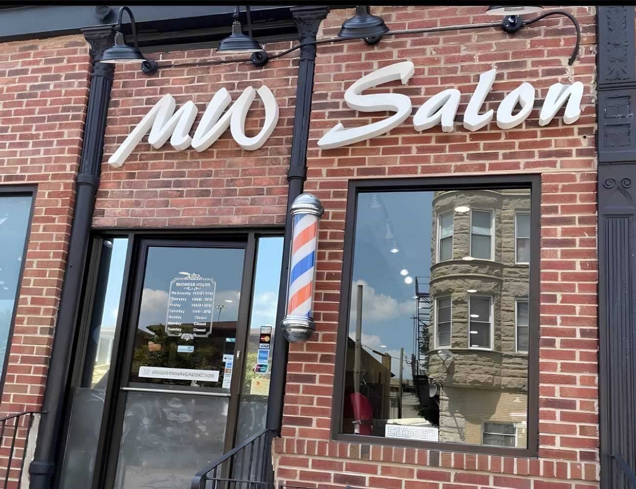 Brick building with "MW Salon" sign and barber pole beside door.